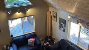 Un saló agradable amb un sostre inclinat, dos sofàs, una taula de centre i una decoració amb una taula de surf.
