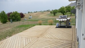 Una terraza de madera con una parrilla y tanques de propano.