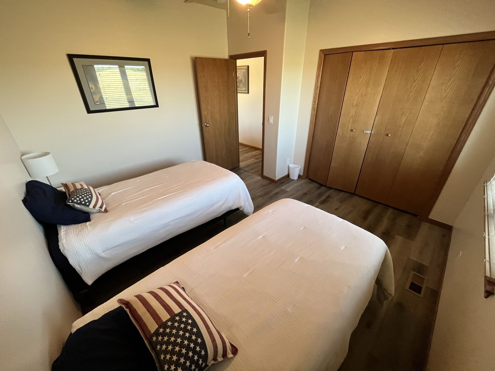 A bedroom with two beds, a wardrobe, a mirror, and a window.