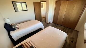 A bedroom with two beds, a wardrobe, a mirror, and a window.