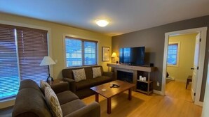 A living room with a sofa, a coffee table, a TV, and a fireplace.