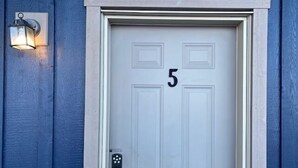 A white door with the number 5, a keypad lock, and a wall-mounted light fixture.