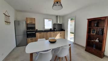 Une cuisine moderne avec un coin repas, comprenant une table blanche, des chaises et un meuble en bois.