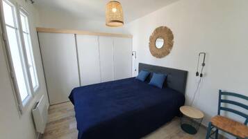 Une chambre à coucher avec un lit, une chaise, un miroir rond et un luminaire suspendu.