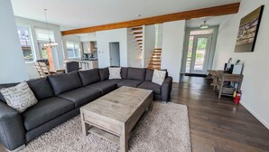 Una sala de estar moderna con un sofá modular, una mesa de centro de madera y un tapete con estampado de espiga.