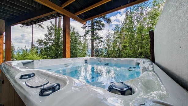 Un jacuzzi con vistas a un bosque y un cielo despejado.