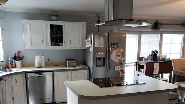 A modern kitchen with white cabinets, a stainless steel dishwasher, a built-in oven, and a central island with stools.