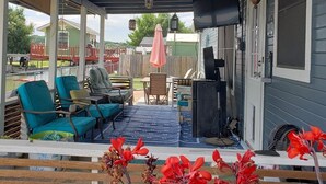 A covered patio with outdoor seating, a television, and a decorative hanging light fixture.