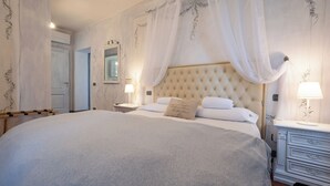 Ein großes Bett mit einem karopolierten Kopfteil, weißer Bettwäsche und einem Nachttisch mit einer Lampe.
