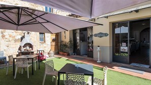 An outdoor patio with a stone wall, a pizza oven, and a covered seating area with tables and chairs. - IL CASTAGNOLO COUNTRY B&B Torre Ardinghelli (San Gimignano)