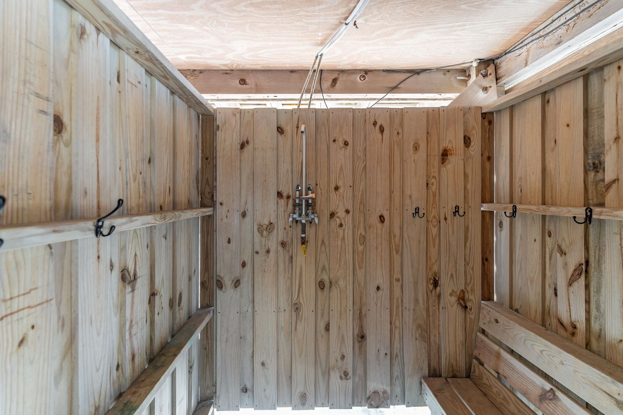 A wooden interior with a central metal fixture, wooden walls, and metal shelves.