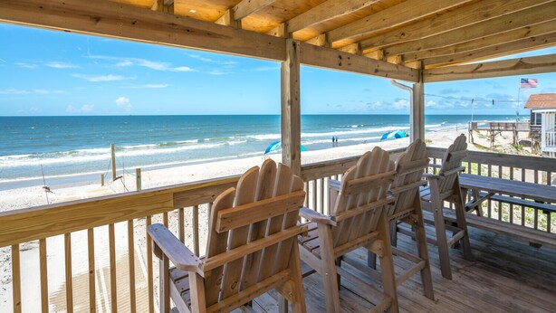 A wooden deck with chairs overlooking a beach. - Oceanfront family fun home and dog friendly! Coastal Coop (Oak Island)