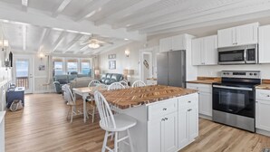 A spacious kitchen with white cabinets, a central island, and stainless steel appliances. - Oceanfront family fun home and dog friendly! Coastal Coop (Oak Island)