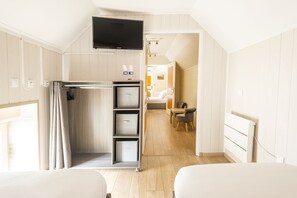 Une chambre d’hôtel comprenant un lit, un téléviseur fixé au mur, un espace douche et un petit coin salon avec une table et une chaise.