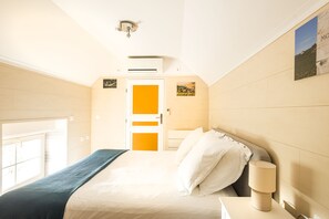 A hotel room with a bed, bedside table, lamp, and a door with a view of the outdoors.
