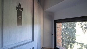 Una puerta con un cartel que dice "TORRE PELLARI" y una ventana con un muro de ladrillo y árboles afuera.