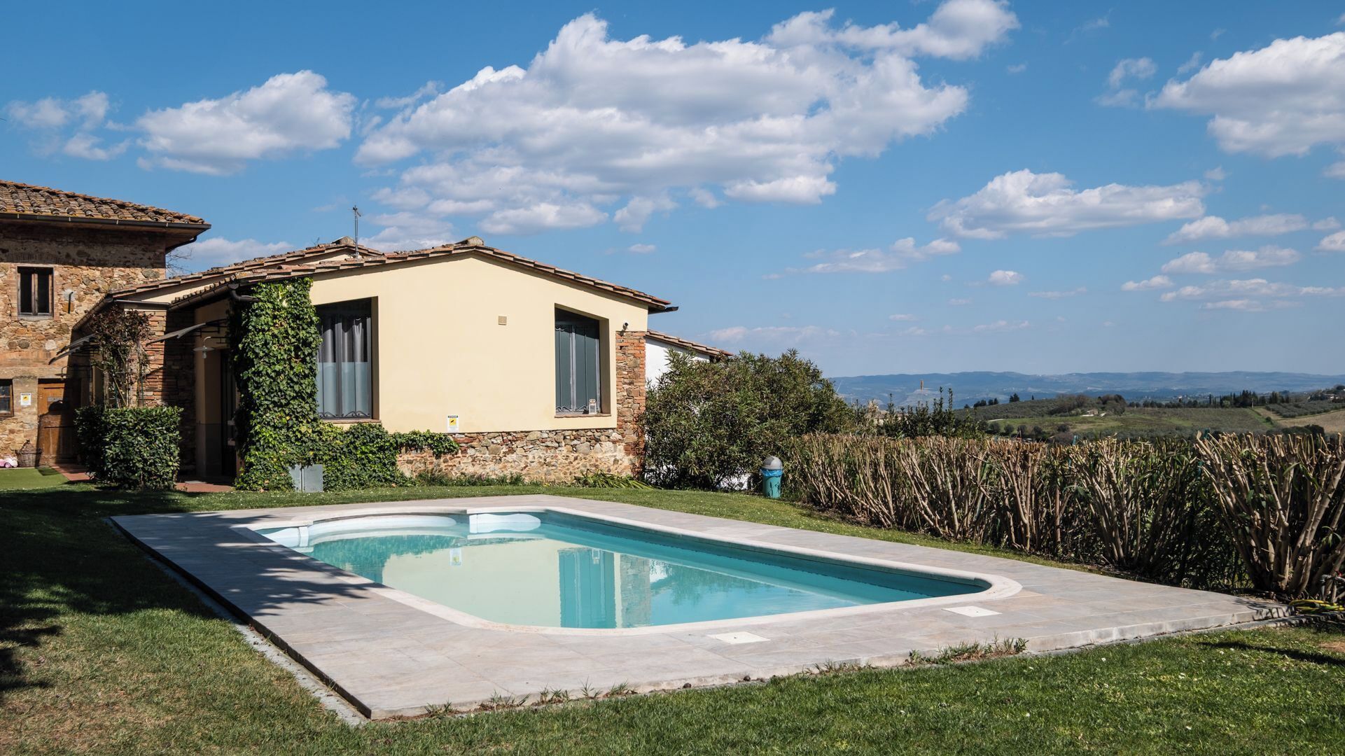 Une maison avec une piscine, des murs en pierre et une vue sur la campagne.