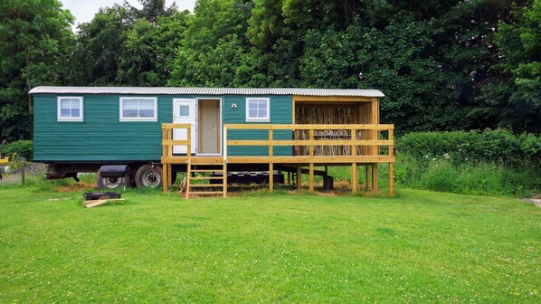 A green mobile home with a wooden deck and a door leading to a small porch. - Unique Upcycled Straw Trailer @ Westcote (Hawick)