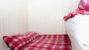 A small, single-bed room with a white wall and a red plaid bedspread. - Unique Upcycled Straw Trailer @ Westcote (Hawick)