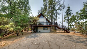 A two-story house with a balcony and a staircase leading to the second floor. - Oakhurst Cabin|Bass Lake View|Game Room|Hot Tub! (Oakhurst)