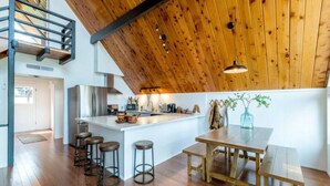 A modern kitchen with a wooden ceiling, a central island with stools, and a dining area with benches. - Oakhurst Cabin|Bass Lake View|Game Room|Hot Tub! (Oakhurst)