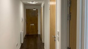 A narrow hallway with wooden doors and a radiator on the left. - WENDY APARTMENT HOME AWAY FROM HOME (Aberdeen)