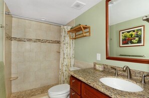 Ein Badezimmer mit Dusche, Toilette, Waschtisch und Spiegel.