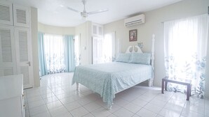 A bedroom with a bed, a ceiling fan, and a window with curtains. - Mira Bay Apartments (Montego Bay)