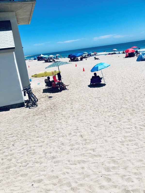 Una playa con sombrillas, sillas y un edificio.