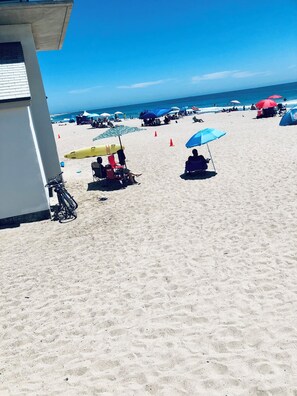 Una playa con sombrillas, sillas y un edificio.