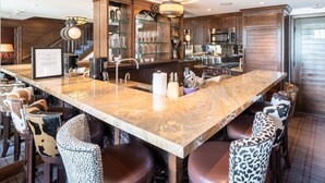 A spacious kitchen with a marble countertop, stainless steel appliances, and a variety of glassware displayed on shelves. - Western Cowboy Quarters steps away from Vail Gondola w/ Hot tub  and  Spa access (Vail)