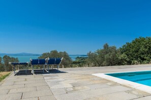 Área da piscina com vista clara para o mar e colinas.