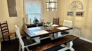 Comedor con mesa de madera, bancos y sillas. Un candelabro cuelga sobre la mesa.