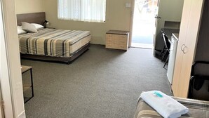 Une chambre à coucher avec un lit, une commode, un bureau et une fenêtre.