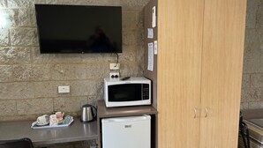 A kitchenette with a microwave, a small fridge, a coffee maker, and a TV mounted on the wall. - Milgate Motel (Casino)