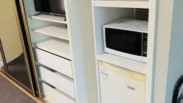 Un depósito de almacenamiento blanco con un microondas, un televisor y un mueble pequeño.