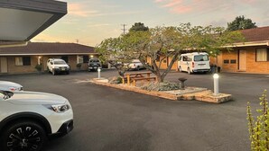 A parking lot with several cars, a picnic table, and a small tree. - Milgate Motel (Casino)