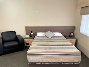 A hotel room with a bed, bedside tables, a chair, and a window with curtains. - Milgate Motel (Casino)