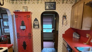 A kitchen with wooden floors, red cabinets, and a red countertop. There are two red rugs on the floor.