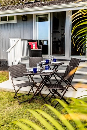 A patio with a table set for two, featuring wicker chairs and a white railing.