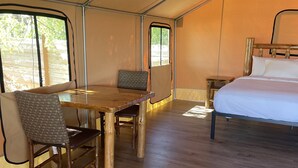 Une pièce aménagée avec une tente, un lit, une table et une chaise.