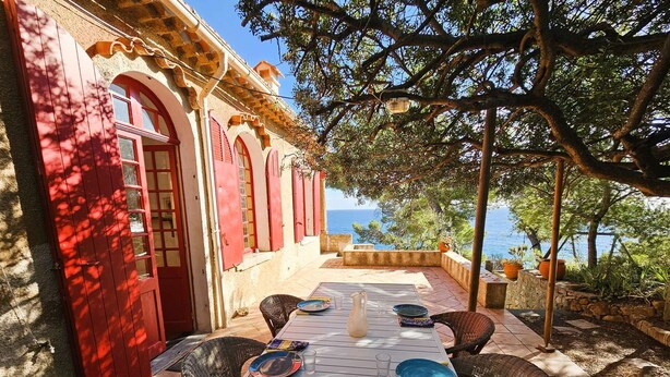 Een terras met een tafel voor twee, met uitzicht op een mooi zeegezicht.