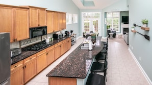 Una cocina moderna con armarios de madera, encimeras de granito y una isla central con taburetes de bar.