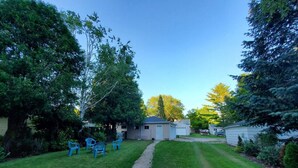 A backyard with a gravel path, a small shed, and a blue plastic chair. - The Cherry Pit - New listing (Sturgeon Bay)