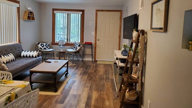 A living room with a sofa, coffee table, two chairs, a TV, and a door. - The Cherry Pit - New listing (Sturgeon Bay)
