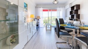 Una cocina moderna con armarios de vidrio, un comedor con mesa y sillas, y vistas al exterior a través de ventanas amplias.