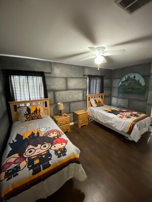 Two single beds with themed bedspreads, a nightstand, and a castle painting adorn this stylish room.