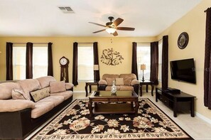 Relax in this stylish living room with a ceiling fan, large flat-screen TV, and comfortable sofas.