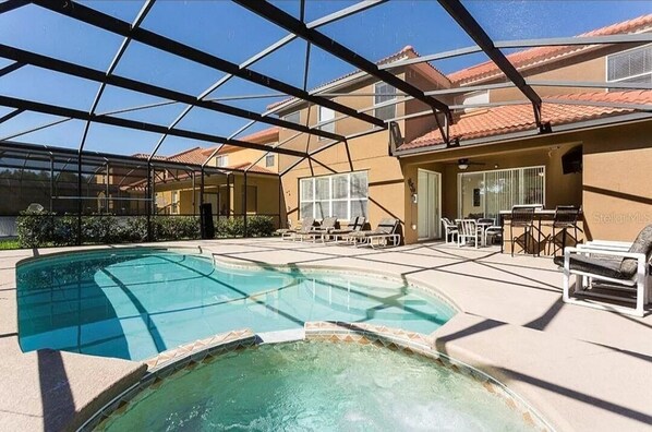 Relax by the pool surrounded by a glass-enclosed area and outdoor furniture.