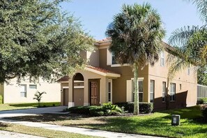 Stunning home with a central entrance, surrounded by lush lawns and palm trees.